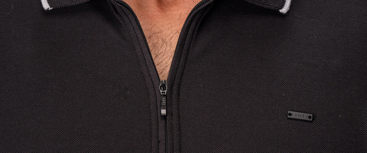 A black zip polo in piqué cotton, close on the collar and the SVNTY tag